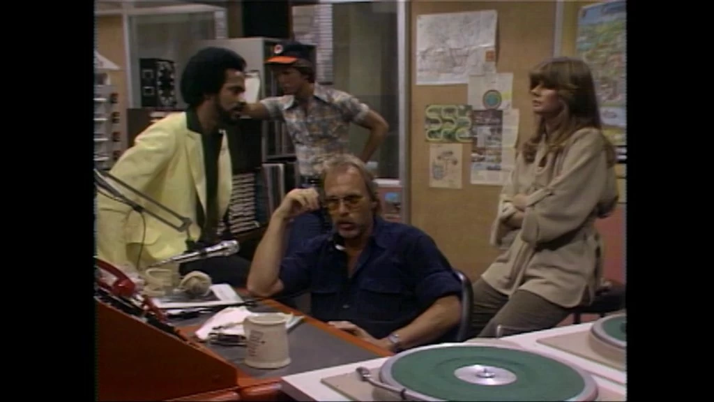 The WKRP in Cincinnati staff listens in horror as Les Nessman reports on live turkeys bombing the Pinedale Shopping Mall.