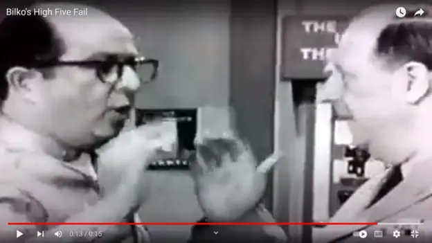 Phil Silvers, as Sgt. Bilko, starts to give his colonel a high-five but thinks better of it.